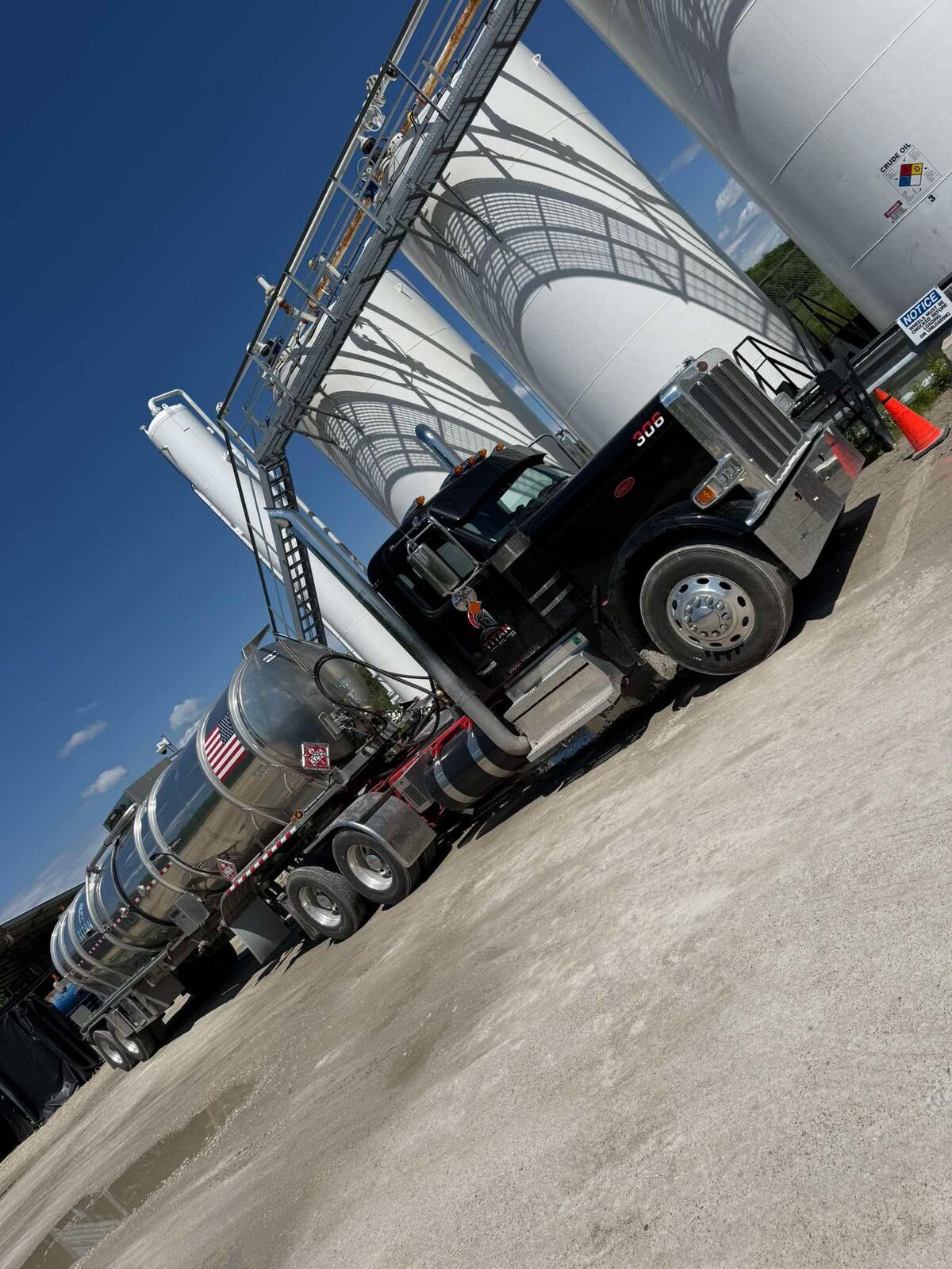 Titan Oil truck 306 hauling crude beneath storage tanks